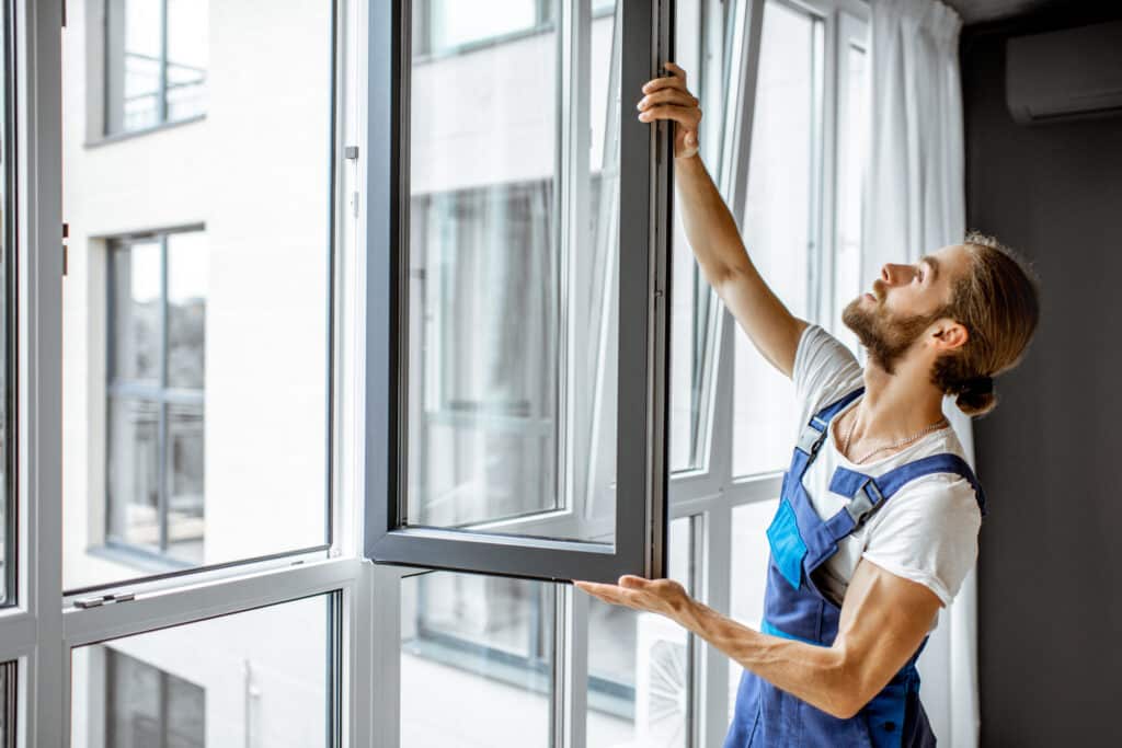Handwerker prüft, ob der Fensterflügel schief im Rahmen hängt