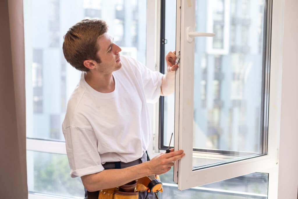 Fenster einstellen: Monteur justiert den Beschlag eines Dreh-Kipp-Fensters